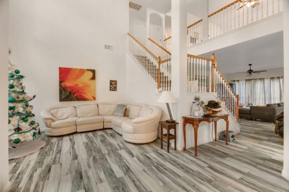 Cozy living room with a cream-colored couch, stairs, and a decorated tree.
