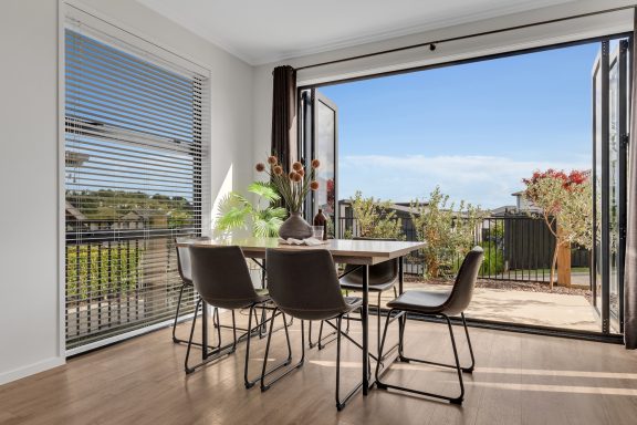 Bright dining area with a table and chairs, open to an outdoor view and greenery.