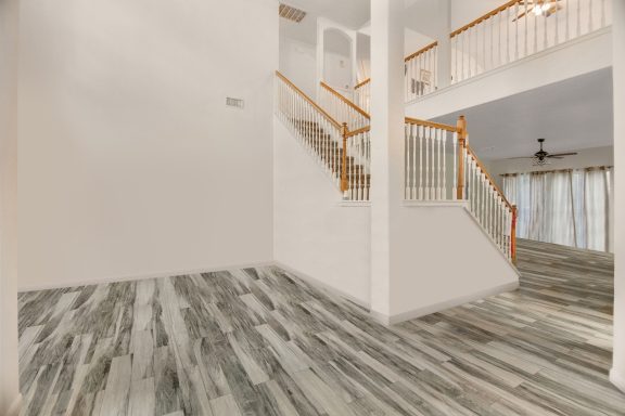 Spacious interior with hardwood stairs and gray patterned flooring.