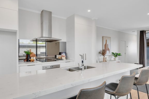 Modern kitchen with a white island, stainless steel appliances, and minimalist decor.