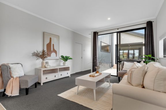 Bright living room with a light sofa, coffee table, and sliding glass doors to an outdoor area.