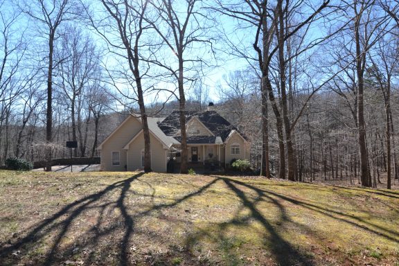 A large house surrounded by trees and shadows on a sunny day.